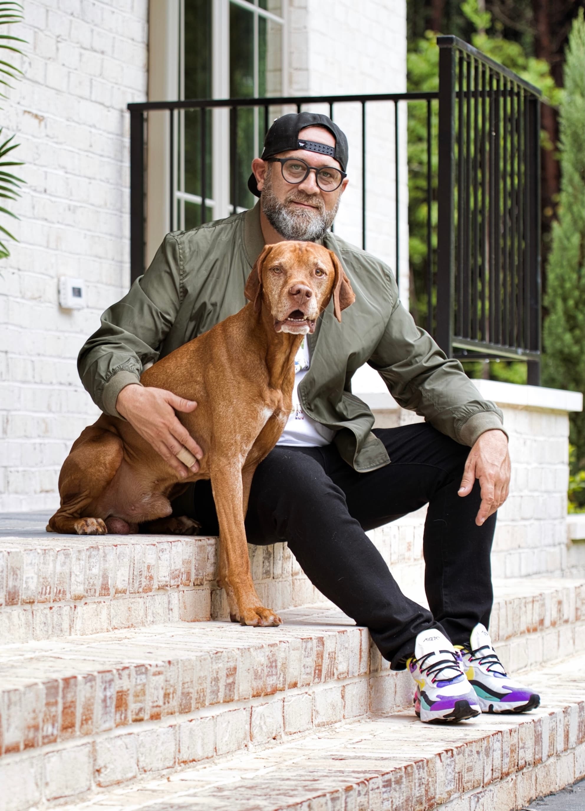 Jonathan Plummer, eXp Realty agent partner and founder of Level House, sitting on front steps with his dog